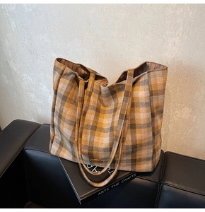 Detail shot of a large plaid tote bag showing its texture and metal logo plate