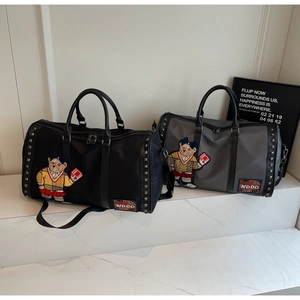 Detailed view of grey and black travel bags with cute bear embroidery and metal studs