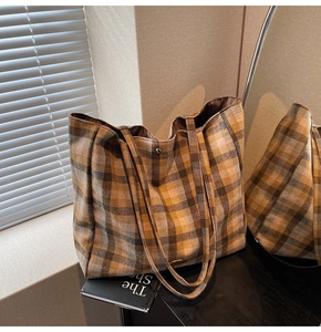 Detail of a large yellow plaid tote bag with high-quality thick fabric and metal logo