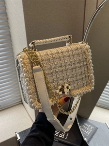 Elegant tweed crossbody bag with pearl trim and gold chain strap in a soft interior setting