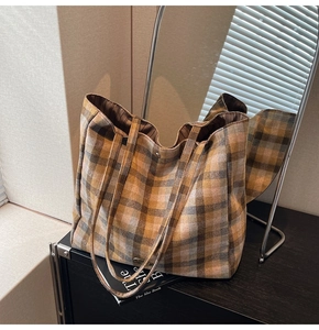 Close-up of high-capacity plaid canvas tote bag with textured fabric and metal logo detail