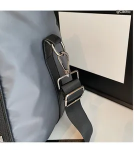 Detail of grey travel bag with silver metal buckle and adjustable black shoulder strap