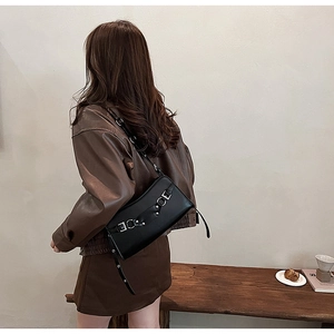 Modern black baguette bag with silver buckles shown on a model in a minimal interior