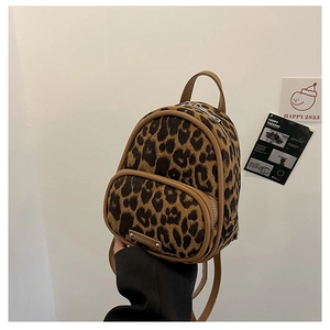 Detail of mini leopard print backpack featuring brown leather trim and metal fashion logo