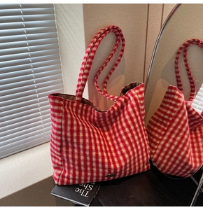 Detail of red and white plaid tote bag texture and metal tag in natural sunlight