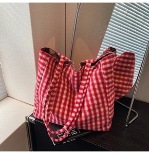 Detail of red and white checkered plush tote bag with silver buckle on a black cabinet