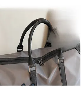 Close-up of waterproof grey travel bag featuring durable black leather handles and zippers