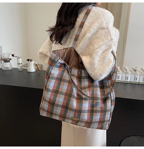 Detail of colorful plaid tote bag with handmade metal plate and striped lining detail