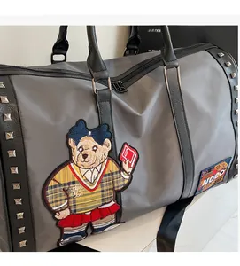 Detail of grey travel bag featuring bear embroidery and silver stud embellishments