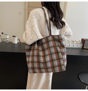 Detail of handmade metal logo on large plaid tote bag for women with tartan pattern