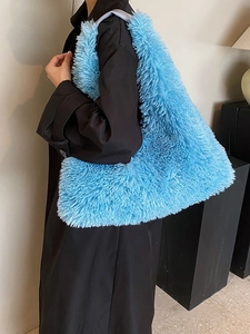 Bright blue plush tote bag with long faux fur, shown on model wearing a black winter coat