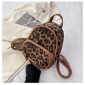 Detail view of mini leopard print backpack with front zipper pocket and metal brand tag