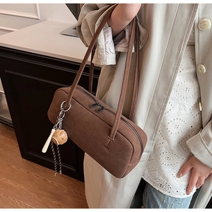 Brown faux suede baguette bag detail showing slim shoulder straps and baseball charm