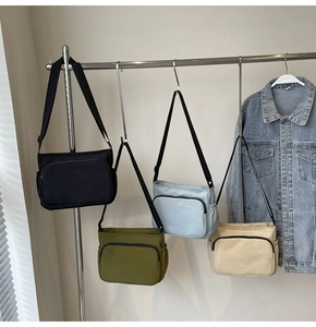 Sacs bandoulière en nylon décontractés en noir, olive, bleu et beige sur un cintre