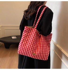 Detailed view of red and white plaid tote bag with plush texture and golden brand tag