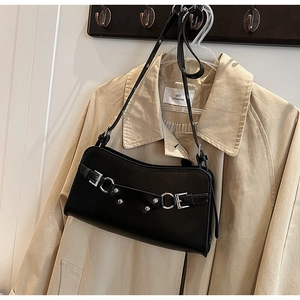Close-up of black leather baguette bag featuring silver buckles and punk stud details