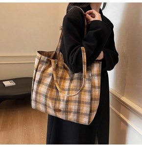 Close-up of model wearing the large plaid tote bag with warm yellow and brown woven pattern