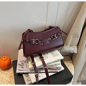 Detail of burgundy leather baguette bag with silver rivets and buckles on magazines