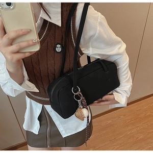 Detailansicht der schwarzen Suede Baguette-Tasche mit Anhängern und Reißverschluss-Detail