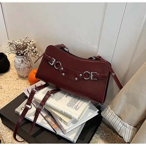 Close-up of deep red leather shoulder bag with silver studs and metal ring details