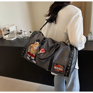 Detail of dark grey travel bag with cartoon bear embroidery and stylish metal rivets