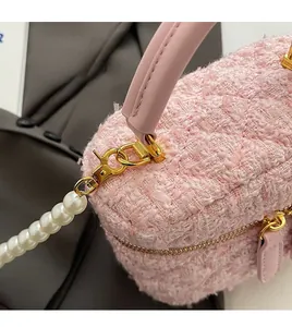 Détail du sac seau en tweed rose avec bandoulière perle et finitions dorées