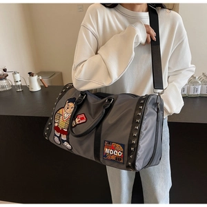 Detail of grey travel bag with bear embroidery, stylish patches, and silver metal studs