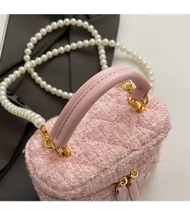 Détail du sac seau en tweed rose avec bandoulière perles et poignée en cuir chic