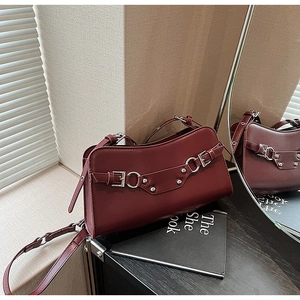 Detailed macro view of dark red leather bag featuring silver buckles and rivet hardware