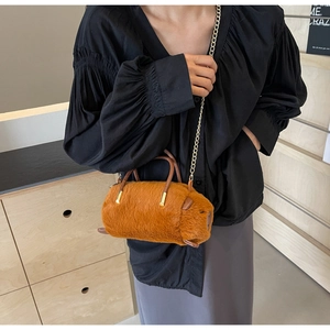 Detailed view of the soft orange faux fur cylinder bag with gold chain strap and handles