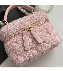 Détail d'un sac seau en tweed rose avec double fermeture éclair dorée et poignée en cuir chic