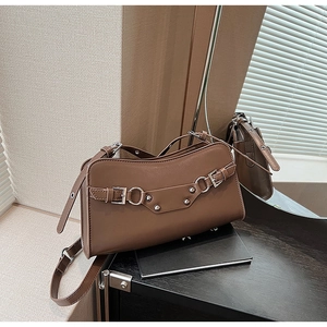 Detail of dark brown baguette bag featuring silver buckles and rivet embellishments