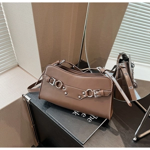Detail view of dark brown leather shoulder bag with silver buckles and stud accents