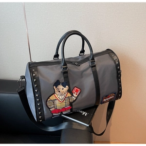 Detail of grey travel bag with bear embroidery, metal rivets and black leather handles