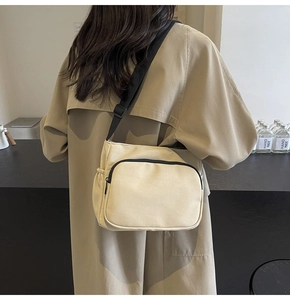 Détail du sac bandoulière en nylon blanc cassé avec sangle réglable et poche latérale