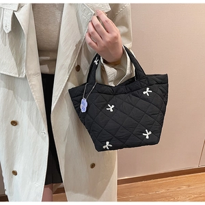 Close-up of black quilted bucket bag featuring white 3D bows and blue cloud charm