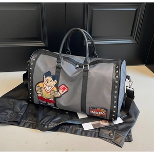 Detail of grey travel bag featuring cute bear embroidery and decorative metal rivets