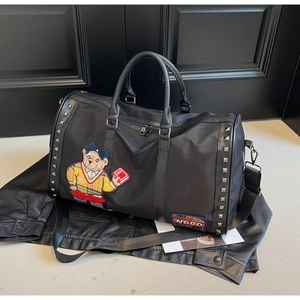 Detail of black travel bag showing nylon texture with a cartoon bear embroidery patch
