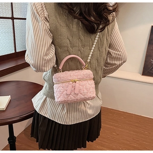 Détail du sac seau en tweed rose avec bandoulière en perles et double fermeture éclair dorée