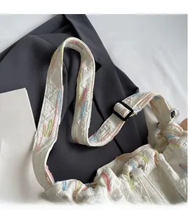 Detail of white canvas bucket bag featuring colorful wave embroidery on the shoulder strap