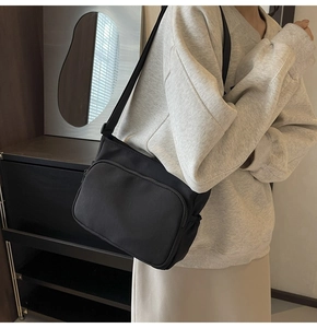 Vue latérale d'un sac bandoulière en nylon noir sur un mannequin pour un look décontracté