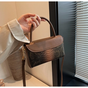 Detail of vintage brown tote bag featuring embossed snake pattern texture and handle
