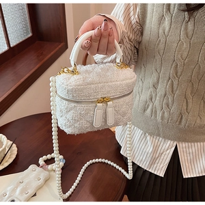 Détail du sac seau en tweed blanc avec bandoulière en perles et fermetures éclair dorées