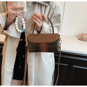 Detailed shot of a brown crocodile pattern handbag with gold hardware and long strap