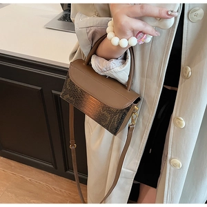 Detail of vintage brown crocodile texture and smooth leather flap on crossbody handbag