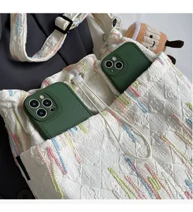Detailed view of white quilted canvas bucket bag featuring dual front pockets and embroidery