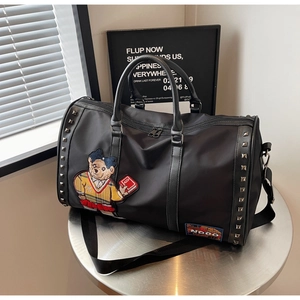 Detail of travel bag with metal studs, embroidery patch, and brand logo on black nylon fabric