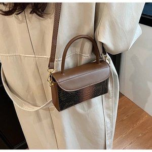 Detail view of vintage brown crocodile texture handbag with gold hardware and strap