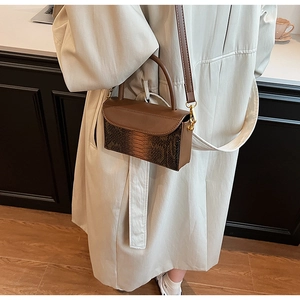 Close-up of vintage brown snakeskin texture handbag with metal buckle and shoulder strap