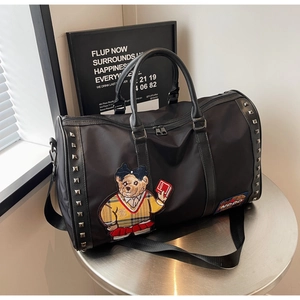 Detail of travel bag featuring silver rivets and a teddy bear patch in plaid sweater